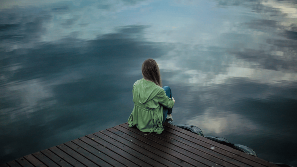 woman sitting on dock struggling with emotional pain